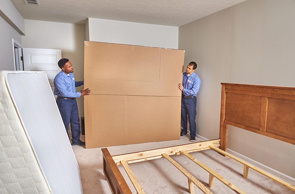 Two movers from Wheaton Worldwide Moving packing up a bed frame